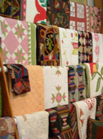 Image of quilts hanging on dowels for display, in the interior of the Rocky Mountain Quilts shop.