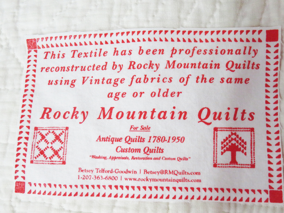Image of the Rocky Mountain Quilts Label. Reads: This textile has been professionally restored by Rocky Mountain Quilts using Vintage fabrics of the same age or older. Rocky Mountain Quilts Antique Quilts 1780 - 1940 Betsey Telford 130 York St York, ME 03909 1-800-762-5914 www.rockymountainquilts.com